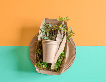 ECO craft paper tableware. Paper cups, plates, bag, fast food containers and wooden Cutlery with cornstarch on a colored orange-blue background. Recycling or the concept of zero waste. The view from the top.